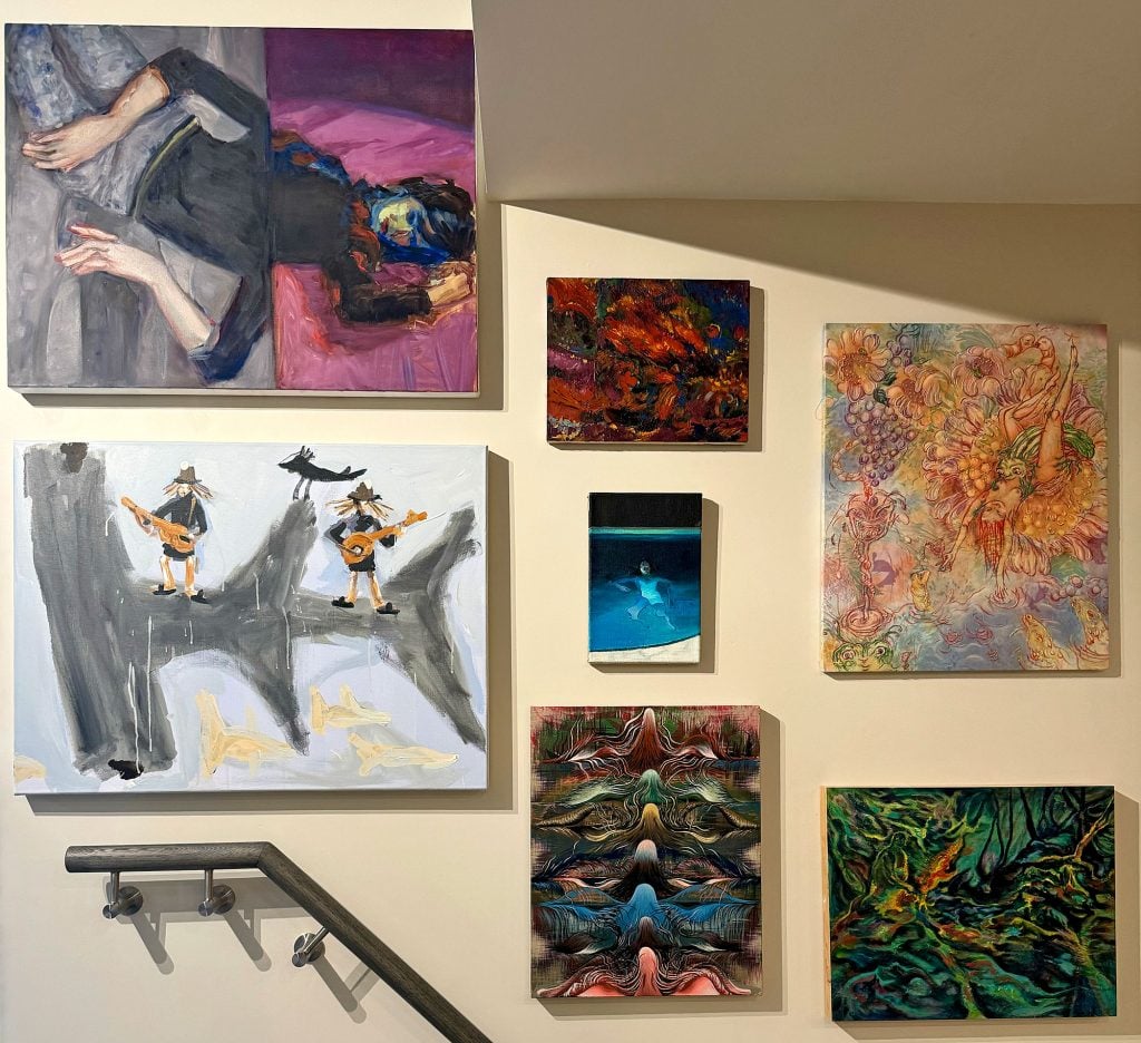 multiple paintings are hung in a gallery wall style setting 