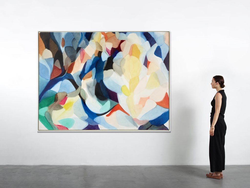 a gallery attendant stands next to a swirly abstract painting