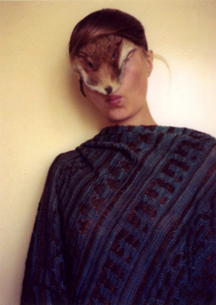 Half portrait of a whoman with the face of a fox fur covering her eyes.
