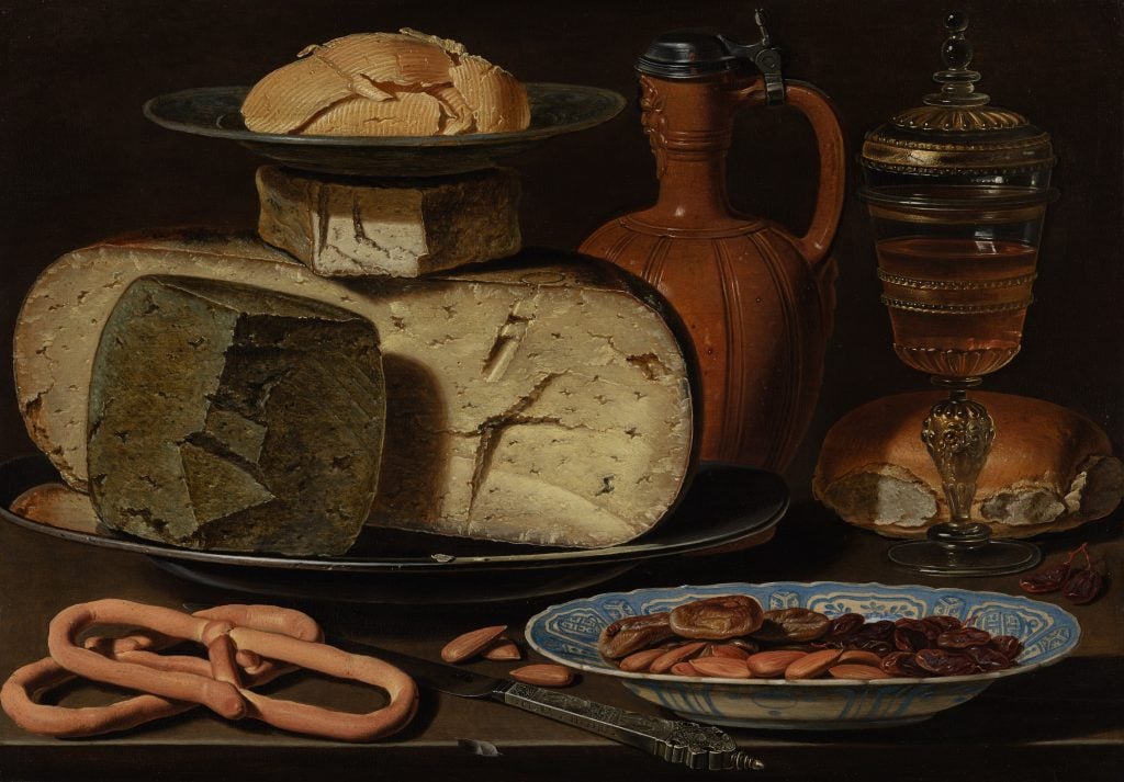 A still life with cheeses, almonds and pretzels sitting on a table