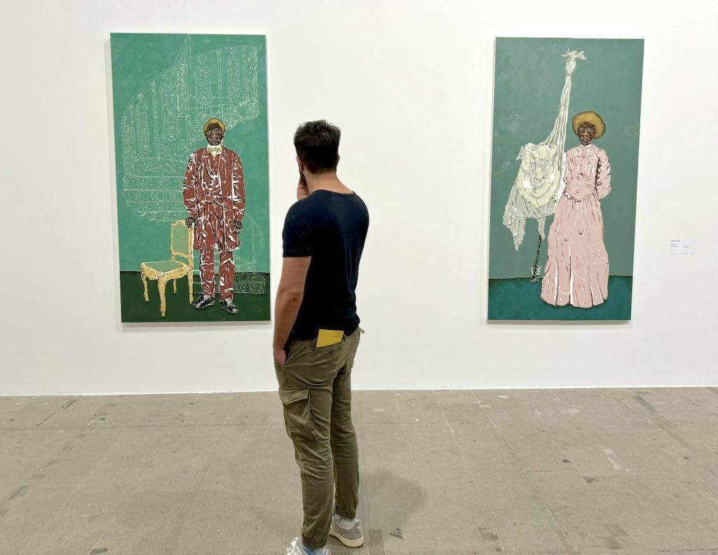 A man contemplates two paintings in an art gallery