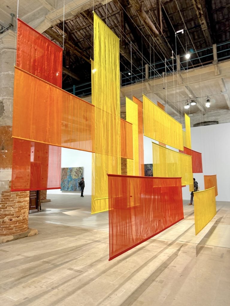 An artwork made of hanging yellow and orange fabric panels