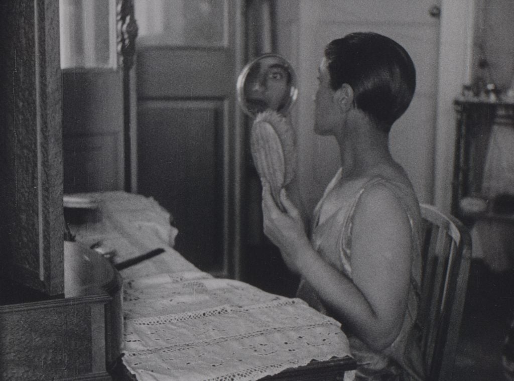 化粧台で鏡を見つめる女性。