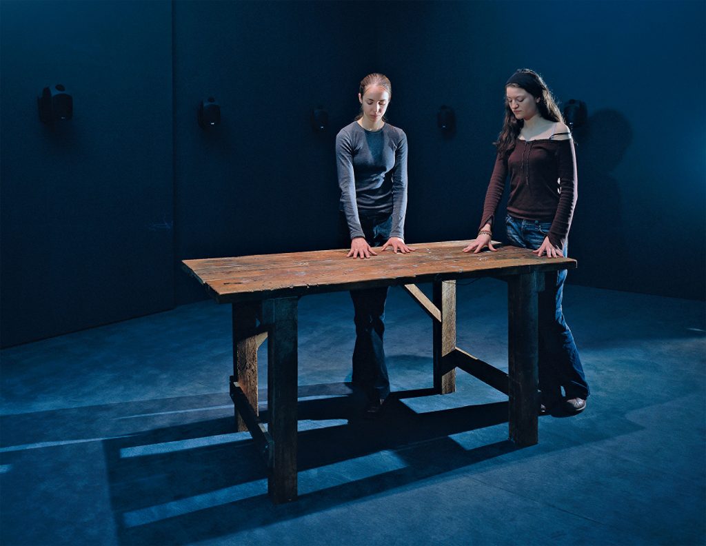 Janet Cardiff, <em>To Touch</em> (1994), installation with wooden table, control circuit box, light sensors, light bulbs, and binaural audio. 
