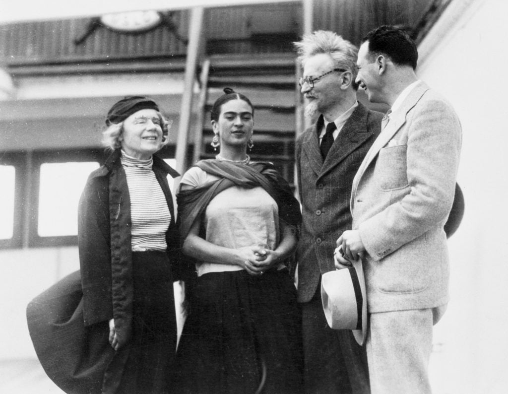 Black and white photo of Leon Trotsky, arriving in Mexico, with his wife, Natalia Sedova (left), is greeted by Frida Kahlo and Max Schachtman, the leader of the American Communist Committee.