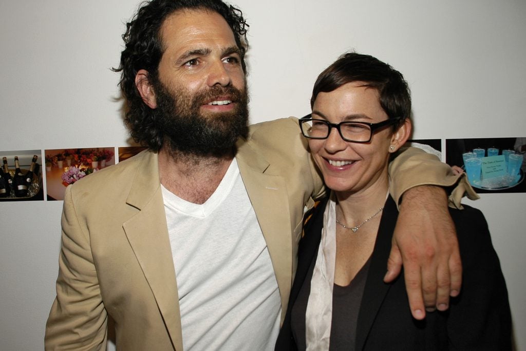 A bearded man, gallerist Gavin Brown, posing with his arm around a woman, artist Elizabeth Peyton