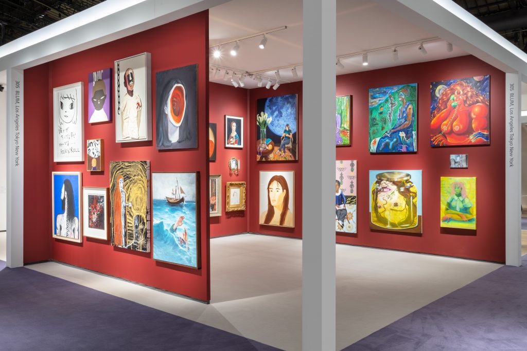 Installation view of a booth at TEFAF New York 2024, where the walls are painted bright red and are covered in multiple paintings in a salon-style hang.