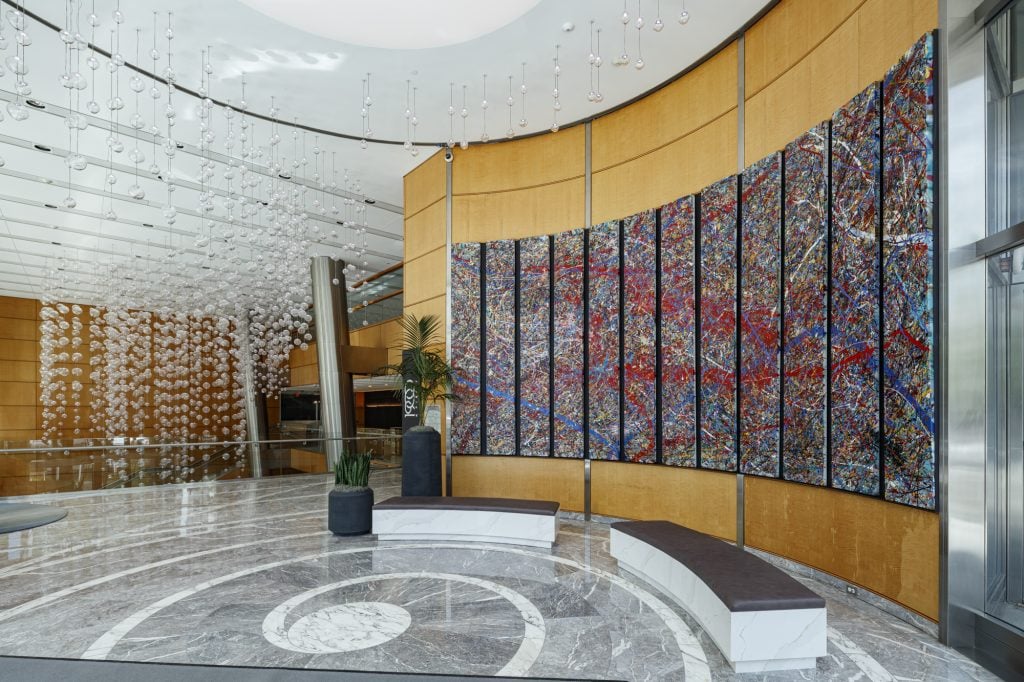 An interior look across the lobby of 1900 K building with the work by Jumper Maybach installed along the right and hundreds of decorative glass orbs hanging from the ceiling.