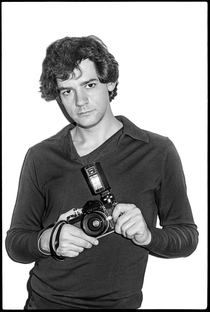 A black and white photo of a young man holding a camera