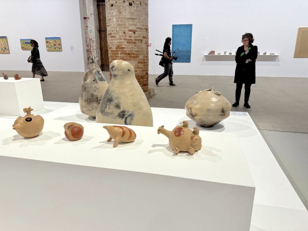 A woman looks at several ceramic objects on a low plinth