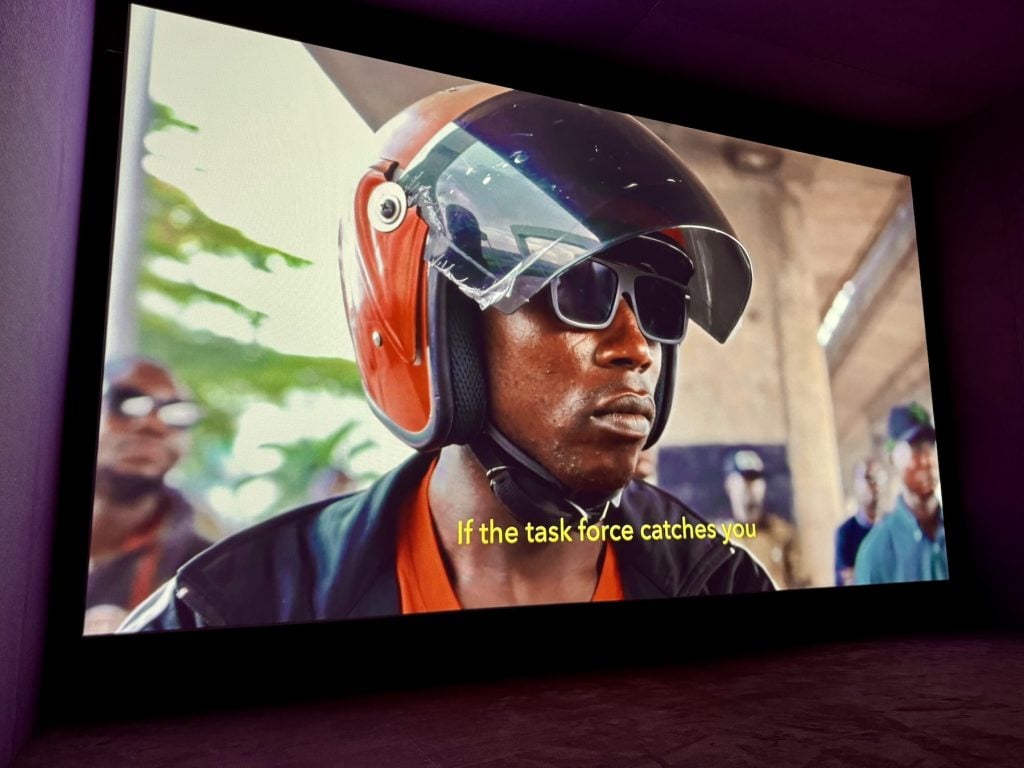 A screen shows a man in a motorcycle helmet and sunglasses