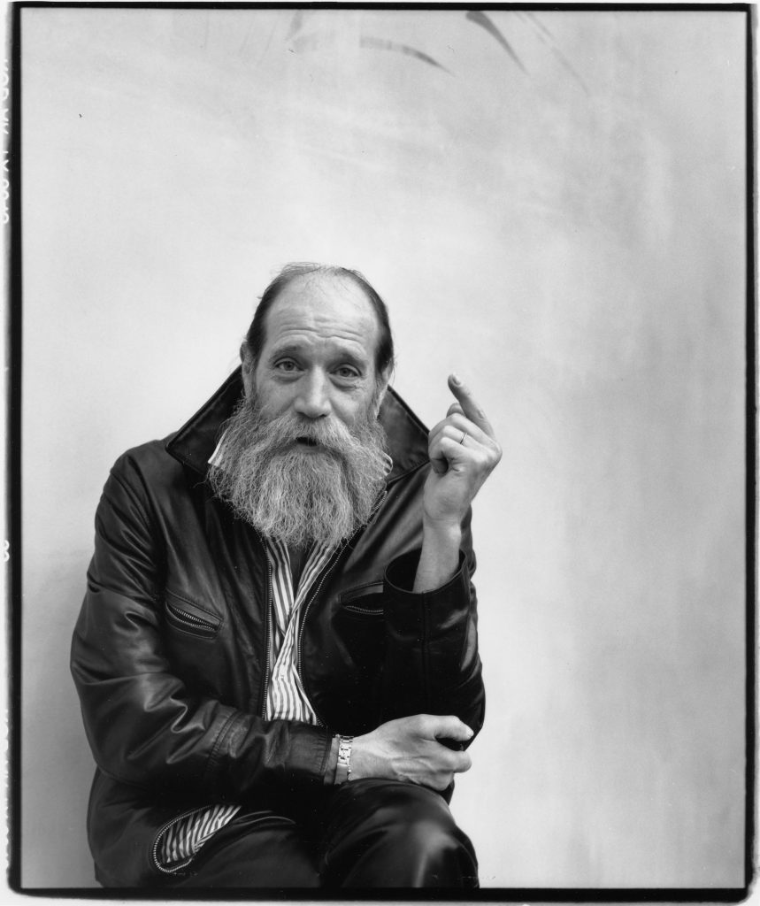 A black and white photo of a man with a beard, identified as Lawrence Weiner.