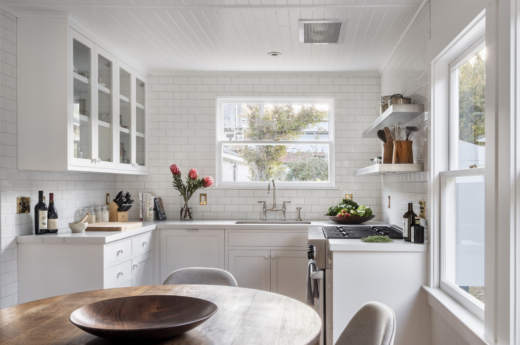 A photograph of a modern, all-white kitchen in a rennovated farmhouse