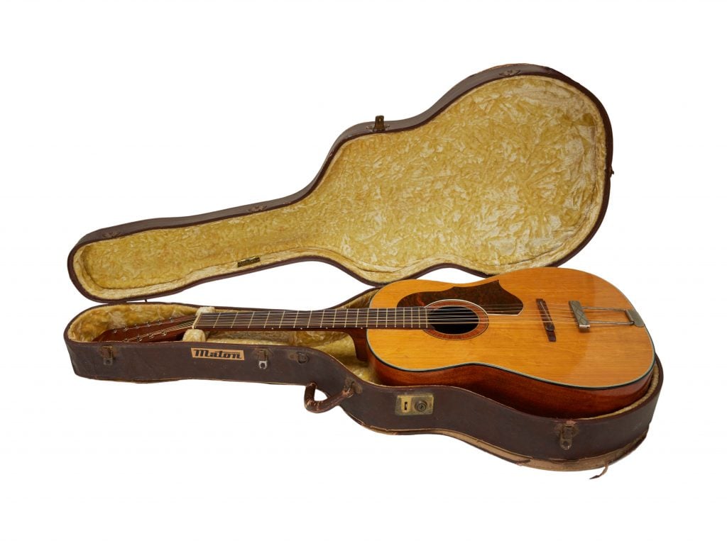 A photo of Lennon's Framus Hootenanny acoustic guitar in an old open case