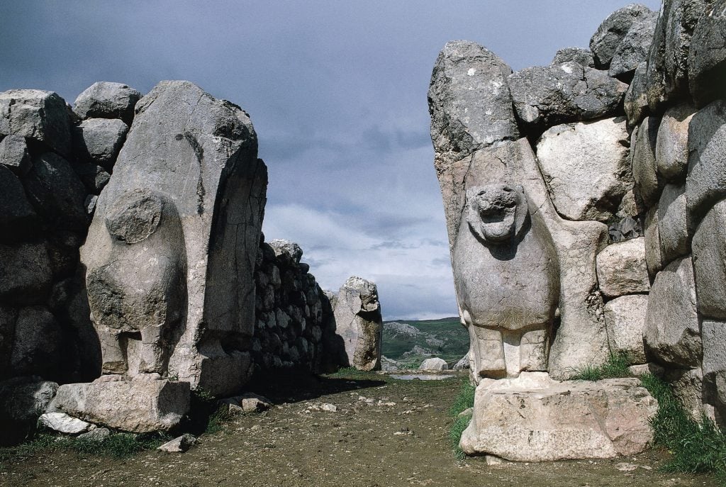 A set of ancient gates made of rock, featuring lion carvings
