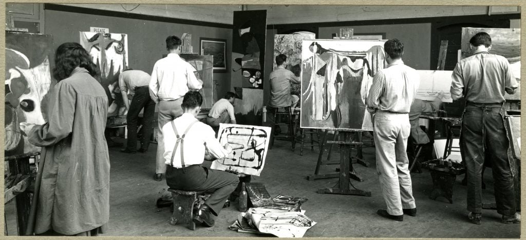 A black and white photograph of students working at their easles in an advanced art class
