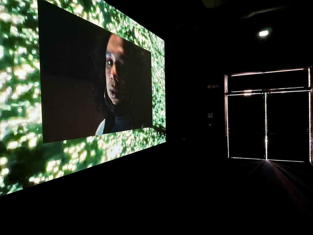 A screen plays an image of a face in a darkened room