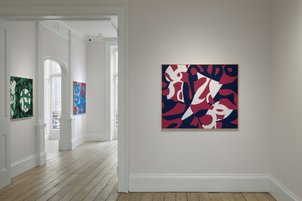 Inside a gallery space with three abstract paintings.