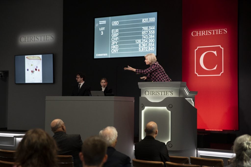 An auctioneer at the rostrum takes bids from auction house specialists