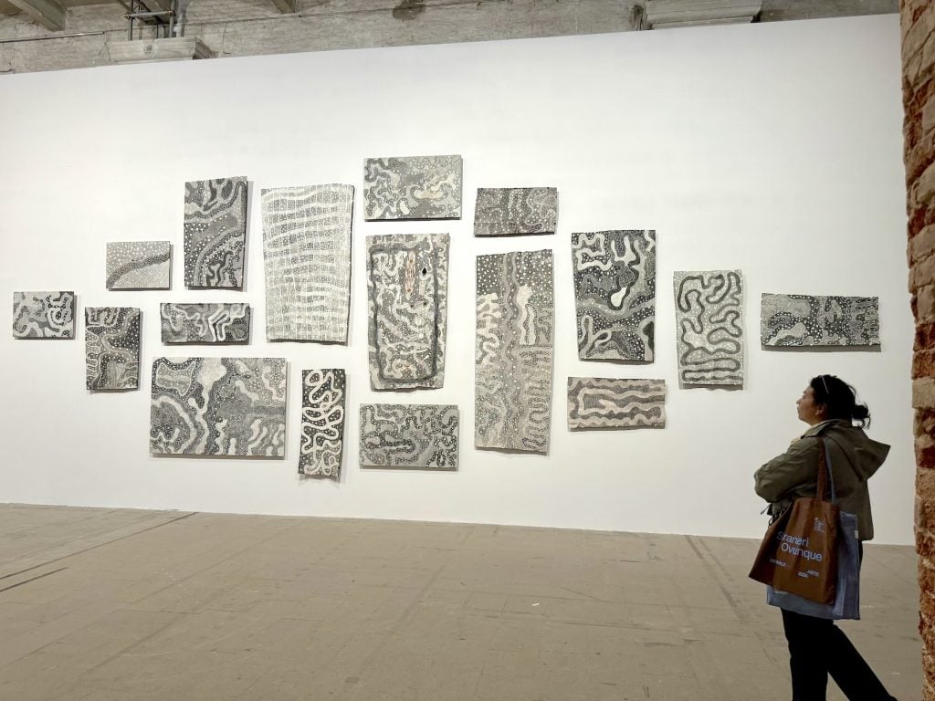 A woman contemplates a multipanel black and white series of paintings