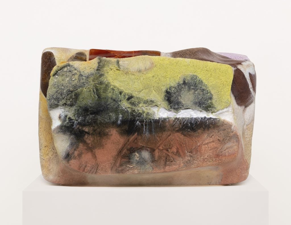 An image of a photographed ice block with multiple colors to it, including yellow-green, burnt orange, and splotches of black