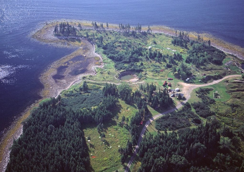 Aerial view of an island lush with greenery and dotted with trees with a lagoon at the center