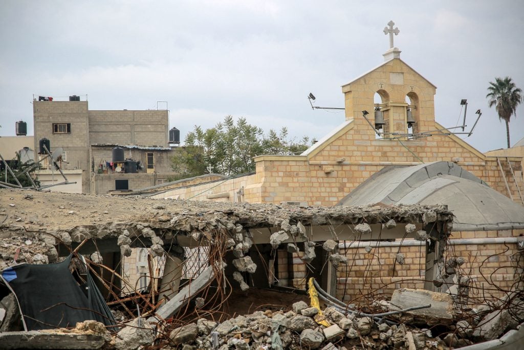 a scene in which a church like building appears to be partially destroyed, surrounded by lots of rubble and broken walls