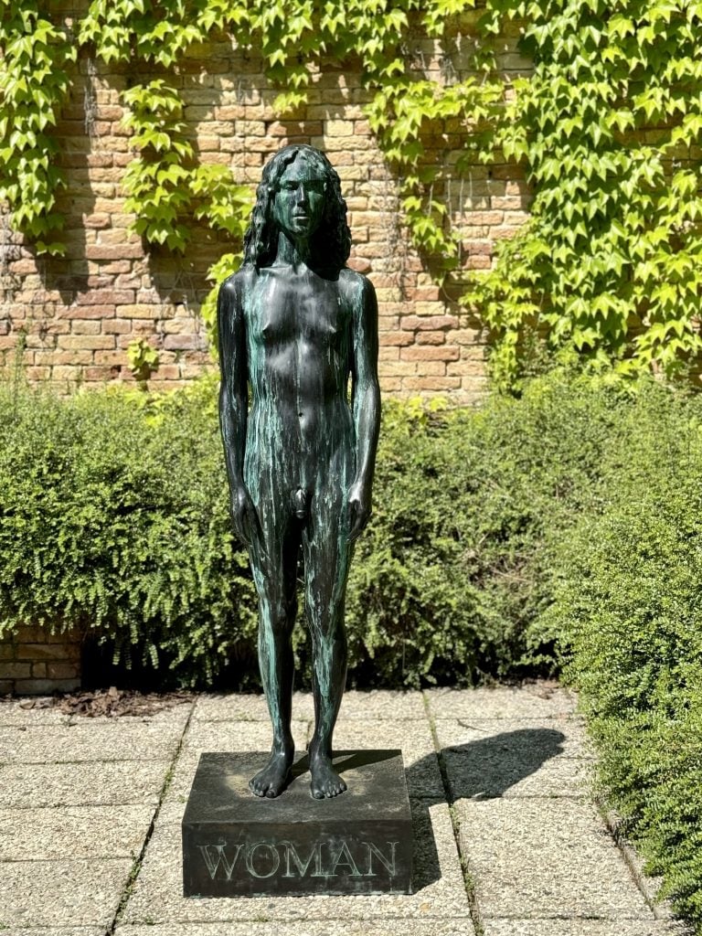 A bronze cast of a trans woman on a base that reads WOMAN