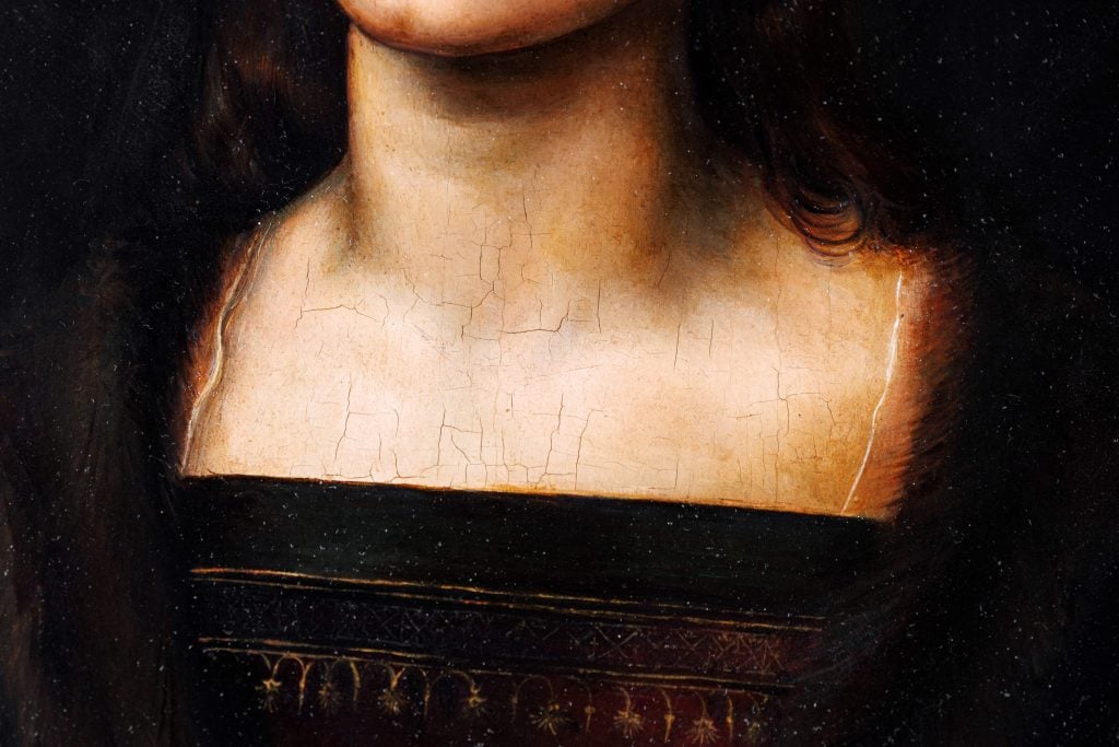 Closeup of a portrait of a woman, showing cracks in the canvas