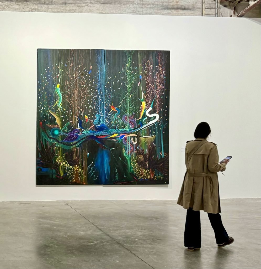 A woman passes a dark toned painting of swirling vegetal abstractions