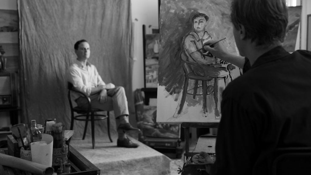 A man sitting for a portrait that another man is painting.