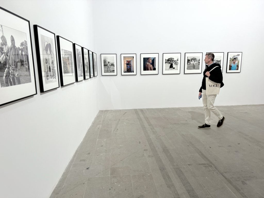 A man walks in front of a row of photos