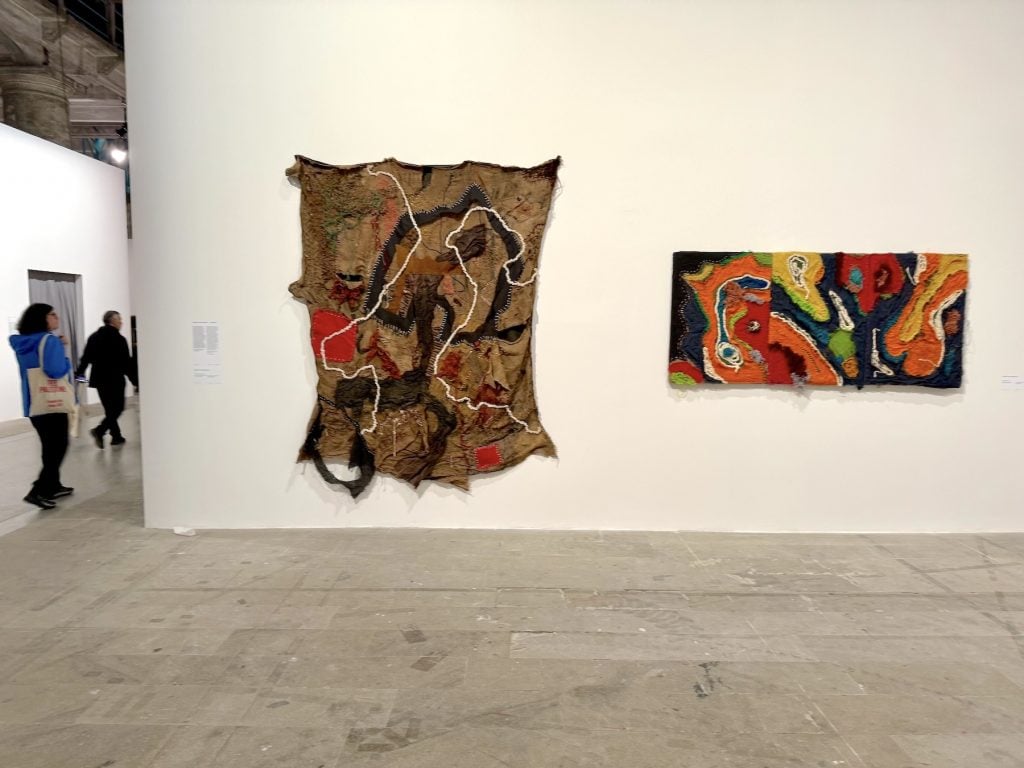 Two abstract textile works hang on a gallery wall