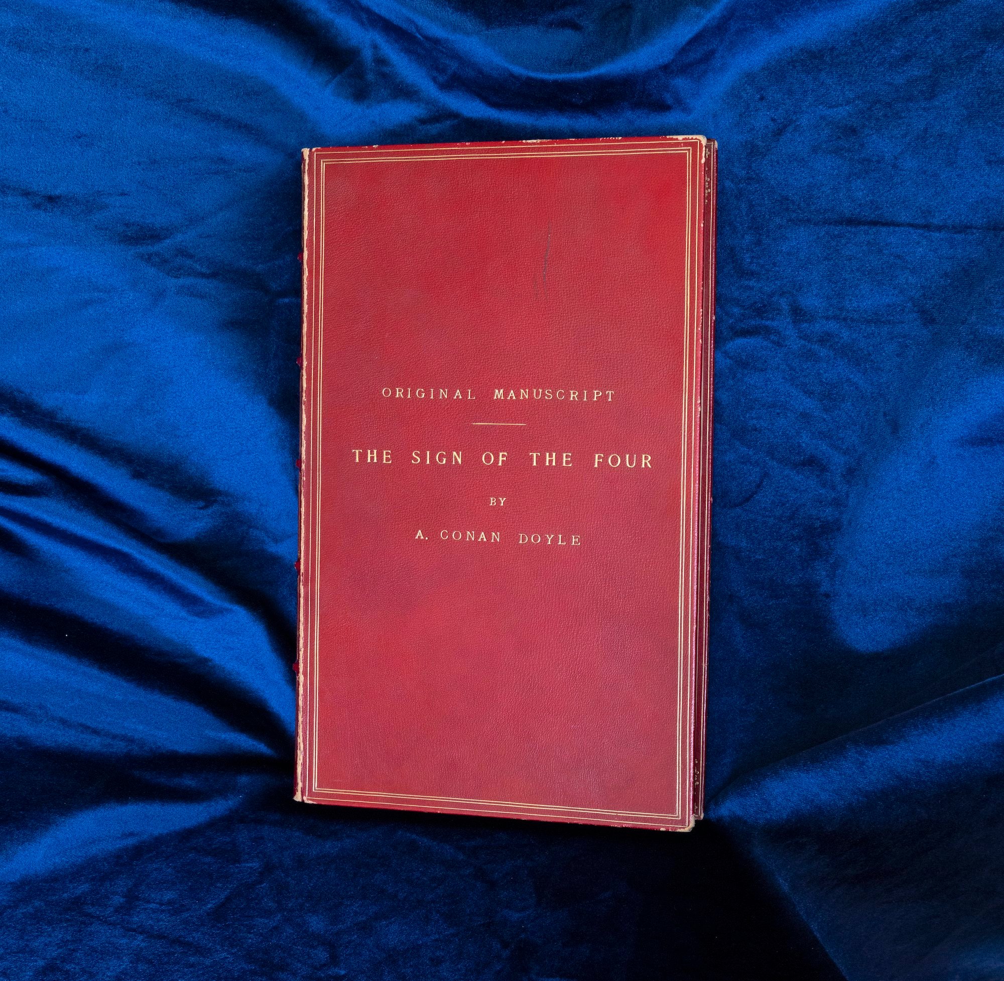 Sir Arthur Conan Doyle's 'The Sign of Four' cover against dark blue fabric.