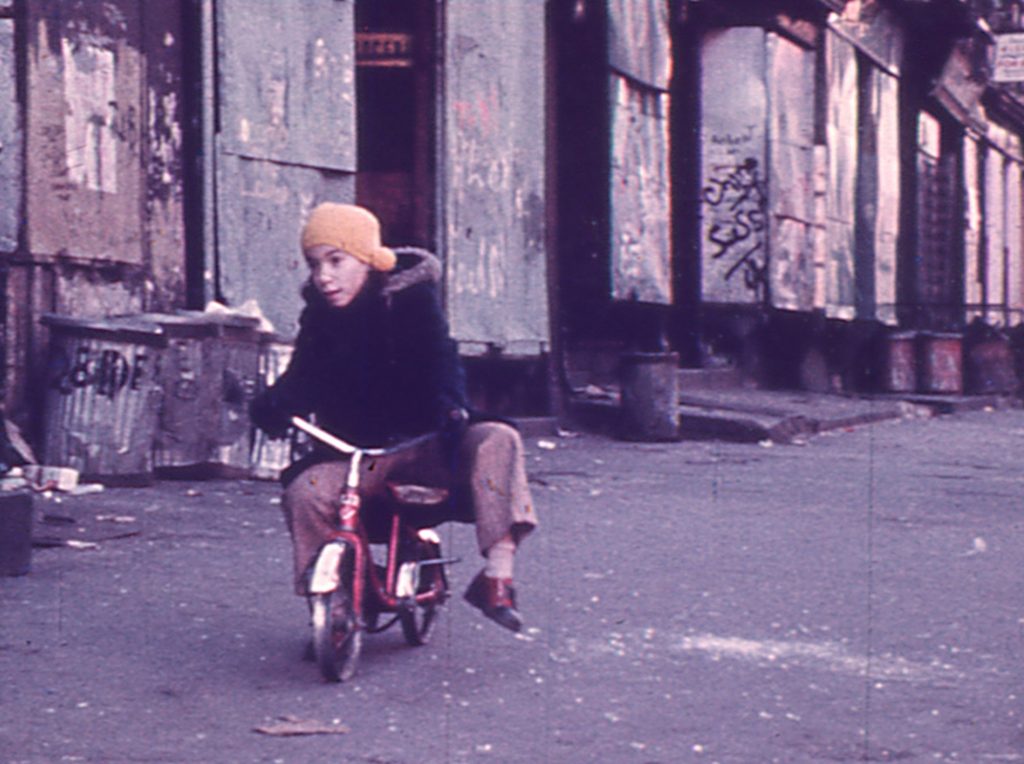 A little boy rides a bicycle on a city sidewalk