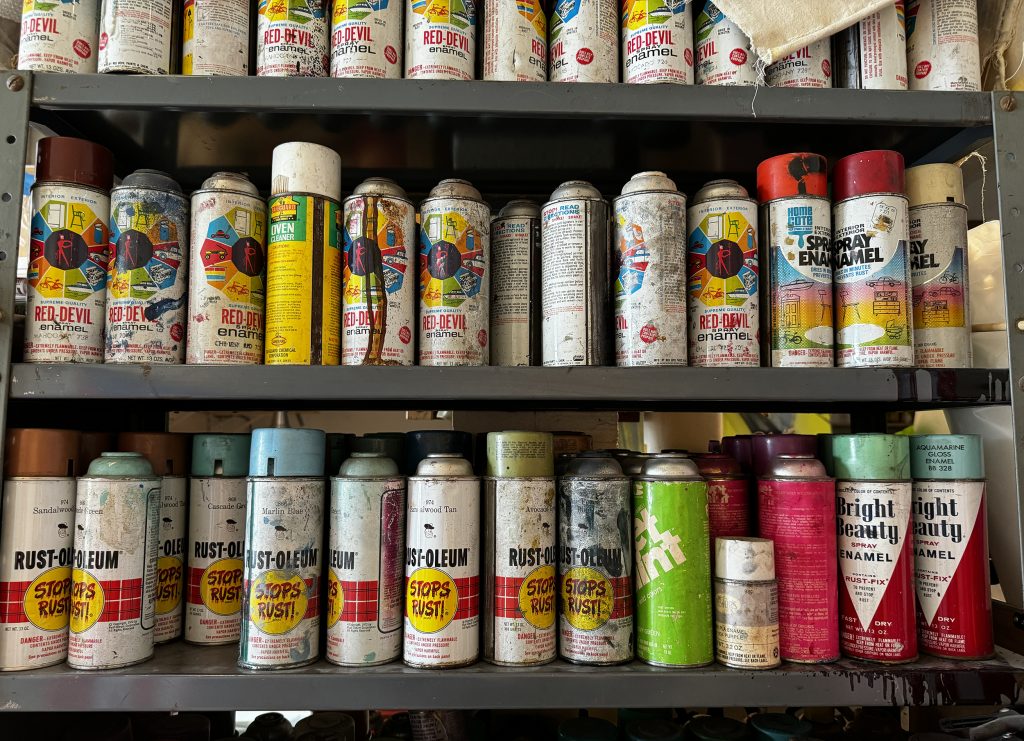 Three shelves filled with spray paint cans in multiple colors