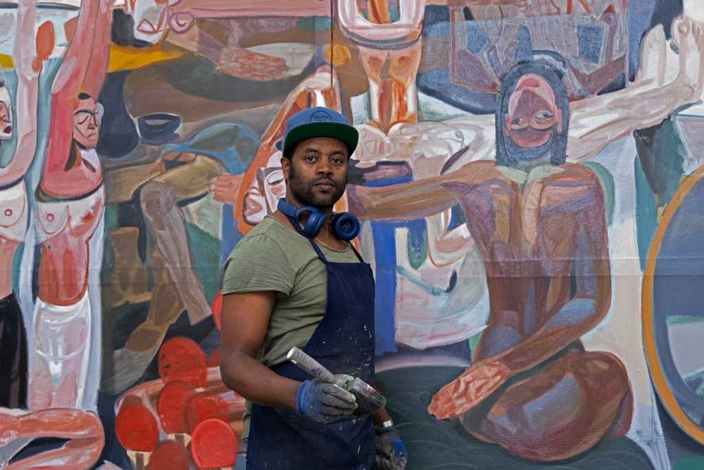 portrait of artist tesfaye urgessa infront of his painting