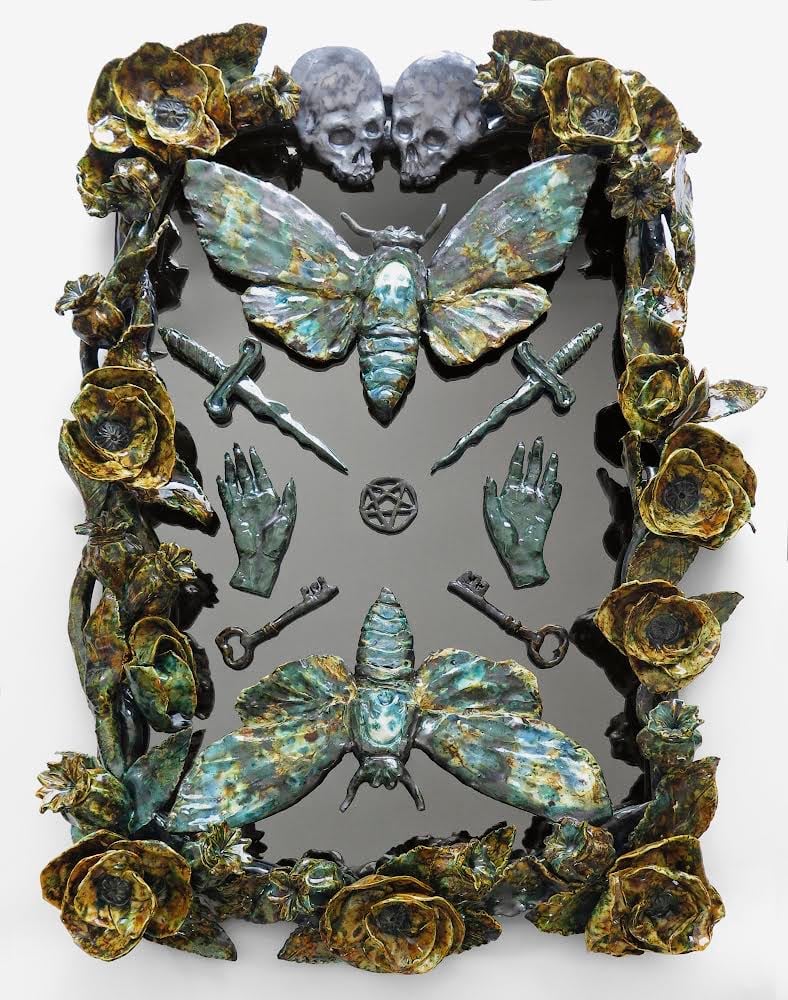 A photograph of a mixed media, sculpted, rectangular-shaped artwork comprised mostly of botanical and insect motifs