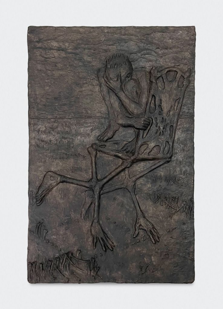 A photograph of a rectangular, portrait orientation artwork which depicts a skeleton sitting despondent in a chair in all black and relief