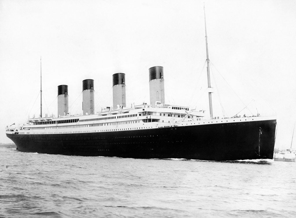 A black and white photo of a huge luxury liner, the Titanic, on waters