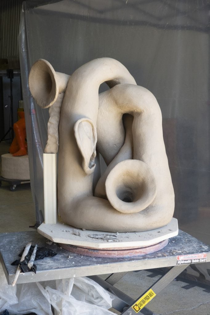 a ceramic sculpture in progress, abstract forms that are anthromorphic, almost like limbs, but with an ear and trumpet shape emerging