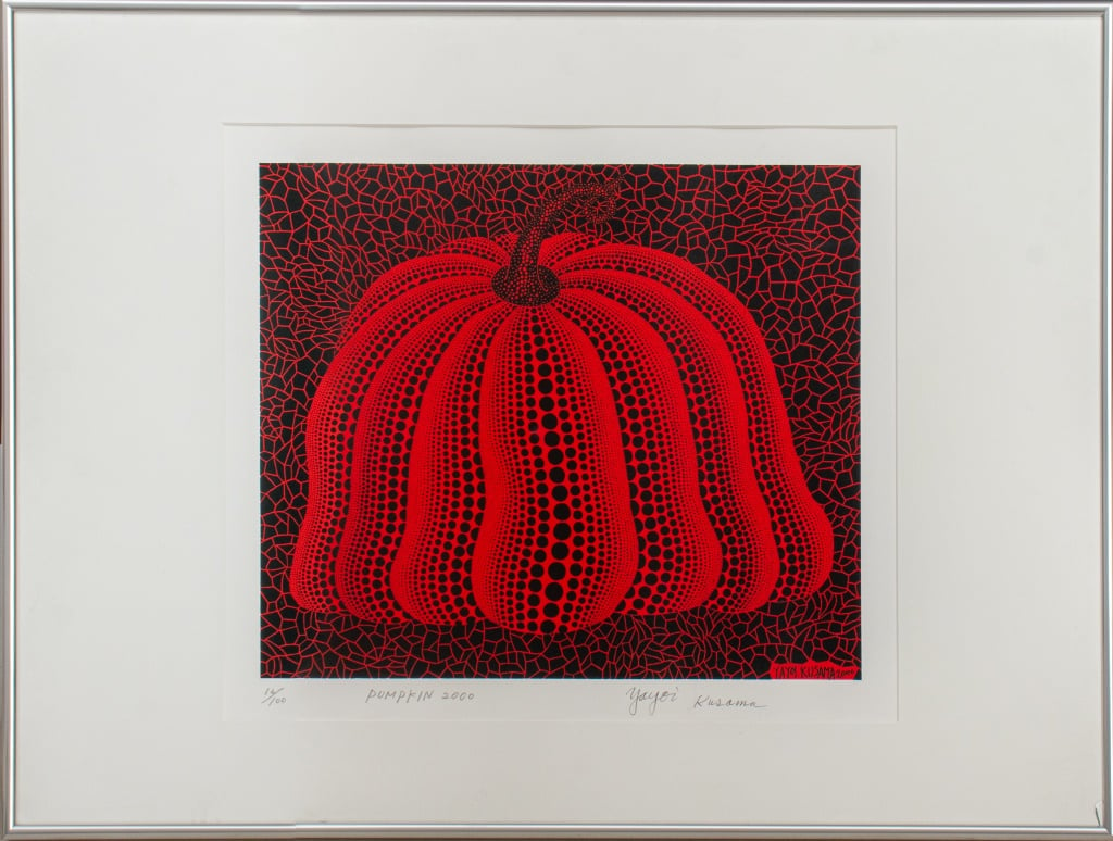 A pumpkin motif made up of varying sizes of black polka dots on red against a black background covered in the inverse red polka dots.