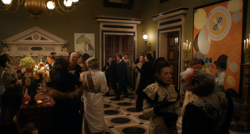 A photo of a film set with a party, with artworks on the wall