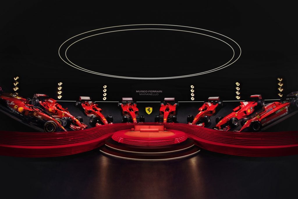 A red-colored circular bed surrounded by Ferrari sports cars