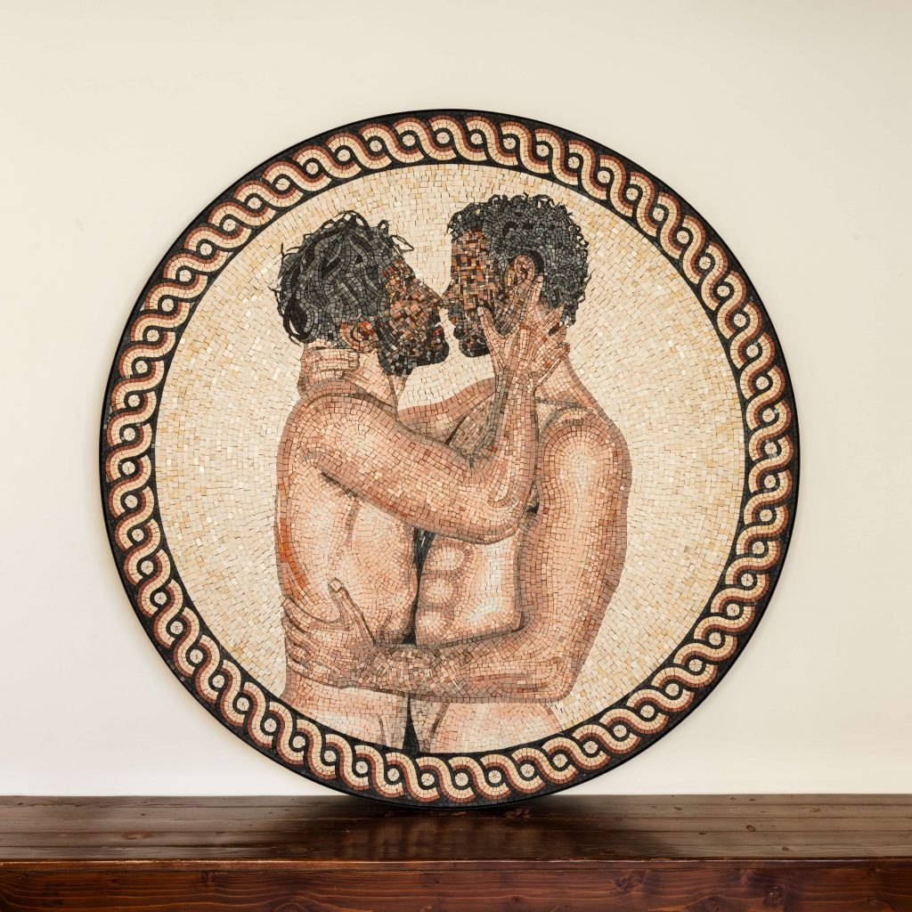 Two men embracing, depicted in a circular mosaic artwork, with intricate details and a spiral border.