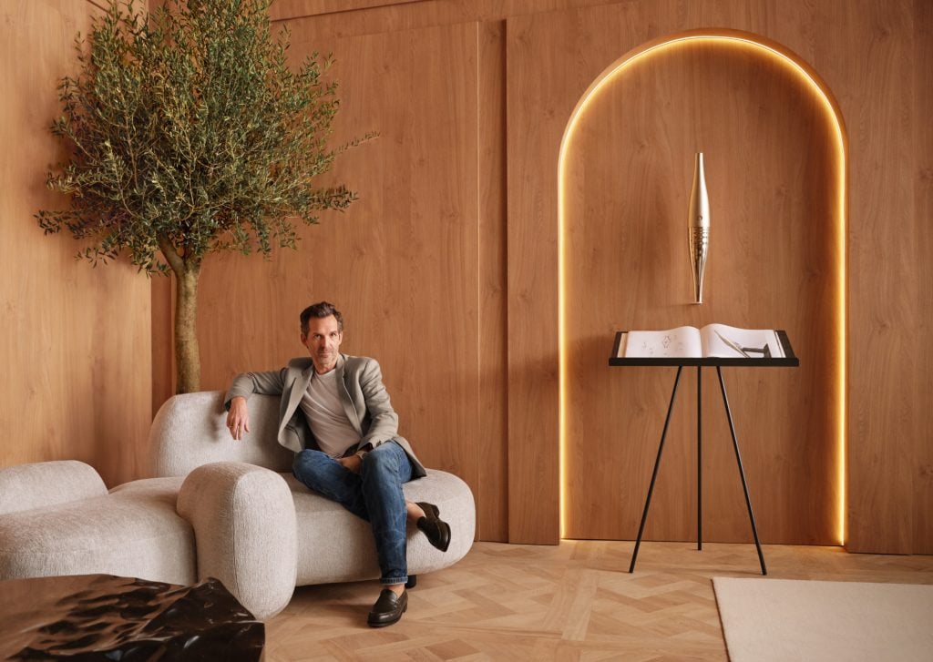 A man sitting in a white sofa in a wood-paneled bedroom