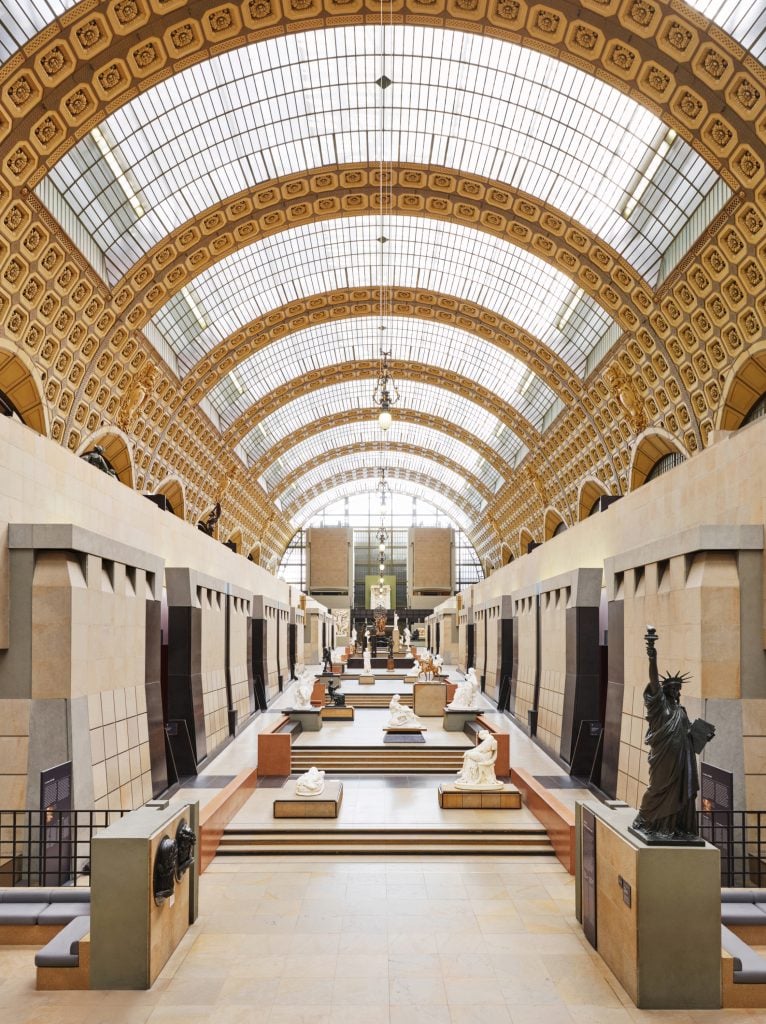 A large hall with massive skylights, with sculptures installed along the sides.