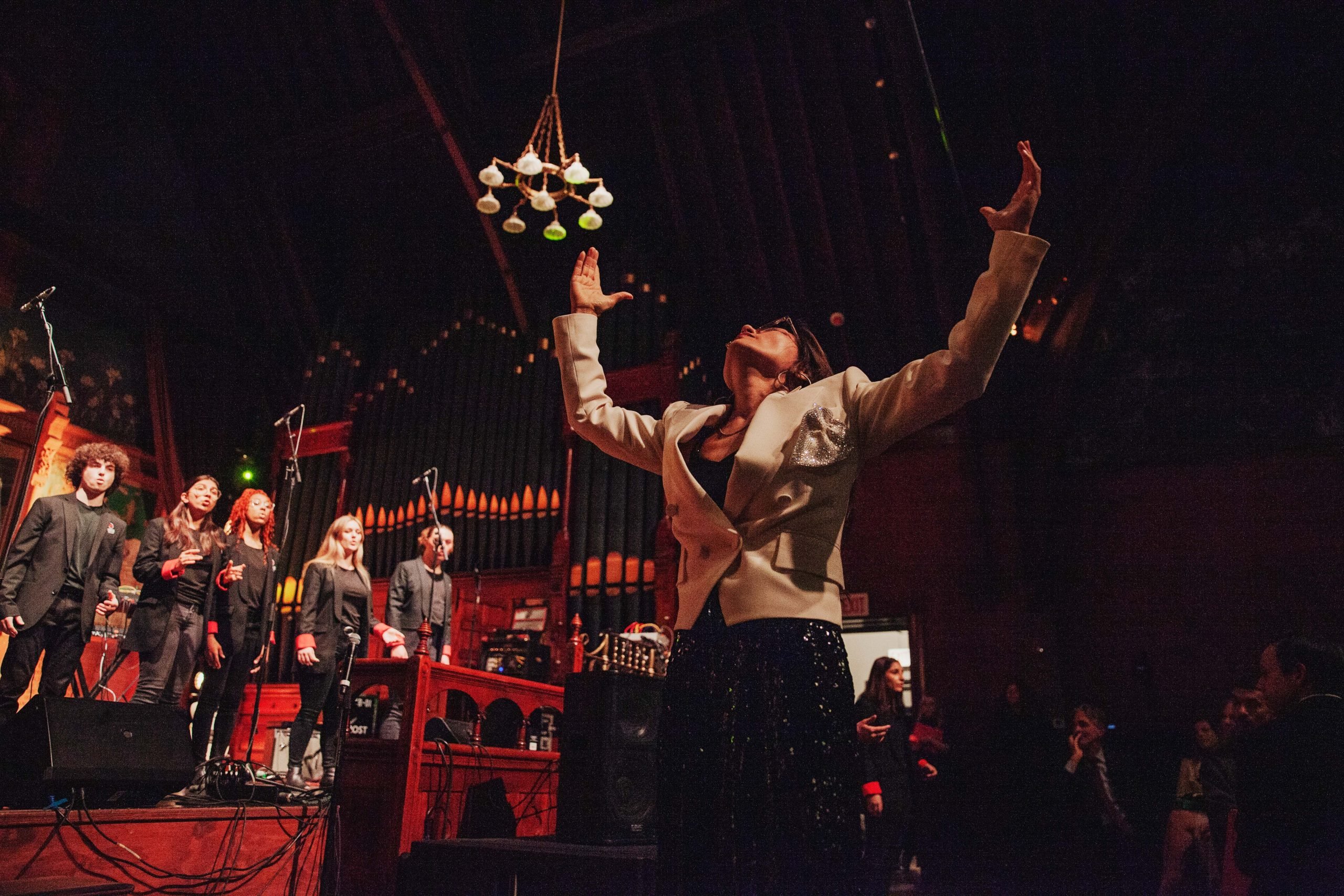 photograph woman looking up to the ceiling singing with both hands raised