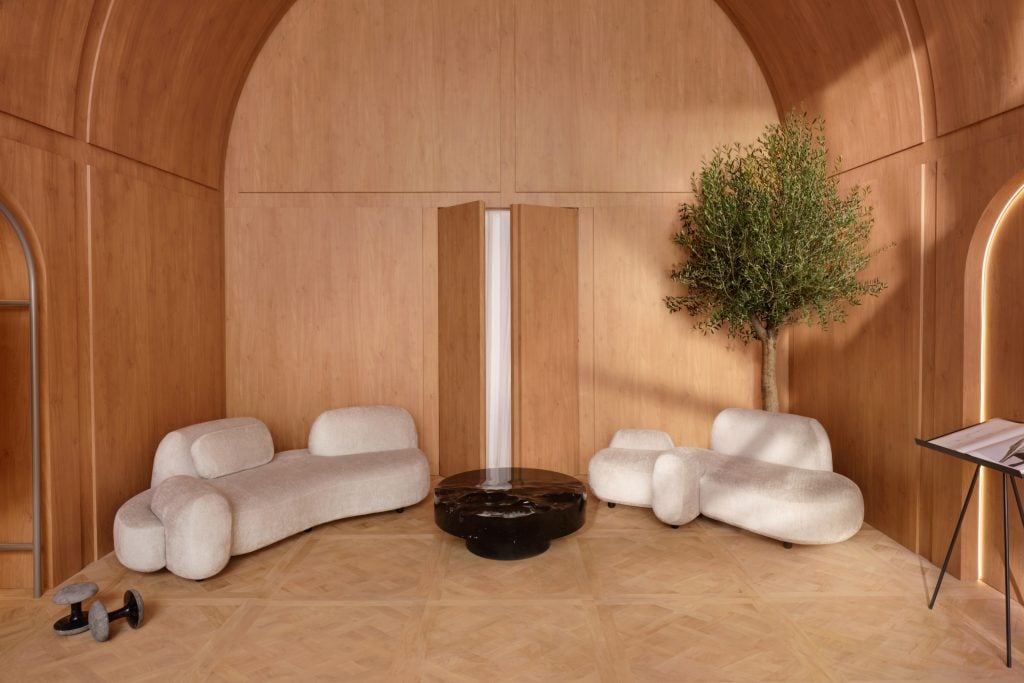 A wood-paneled lounge area furnished with white organically shaped sofas