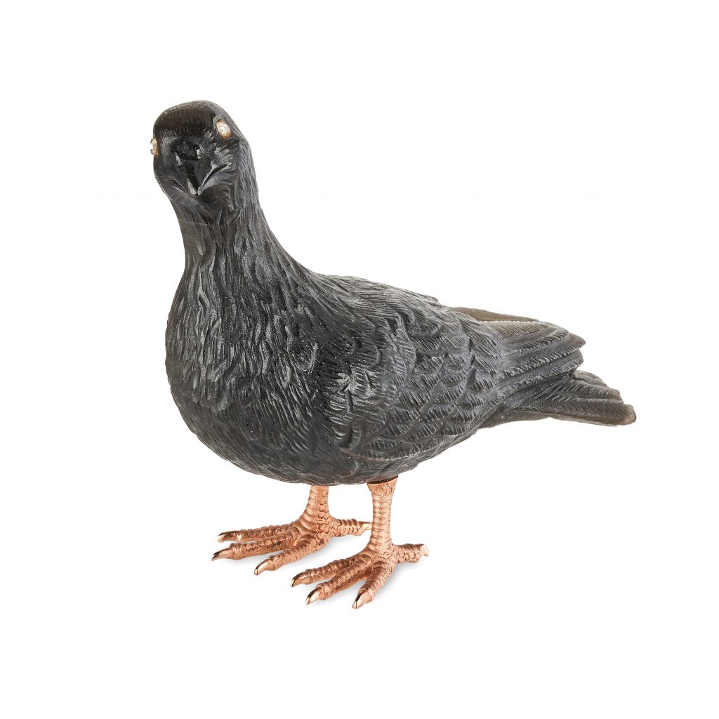 A dark brown carving of a pigeon with gold feet, on a white background. By Fabergé